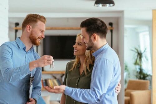 A real estate agent handing over keys to a couple
